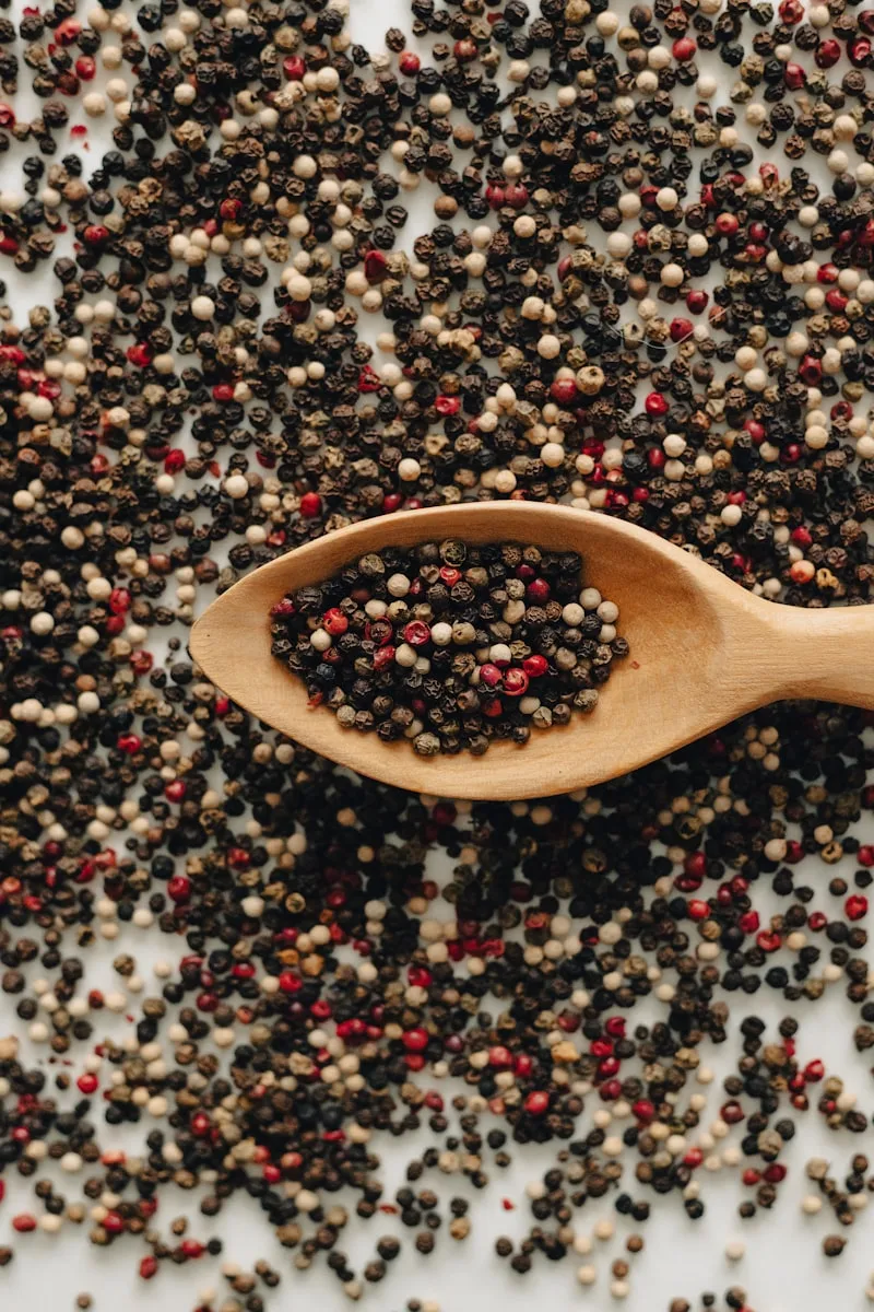 Dry black peppercorns and aromatic cloves in clay bowl
